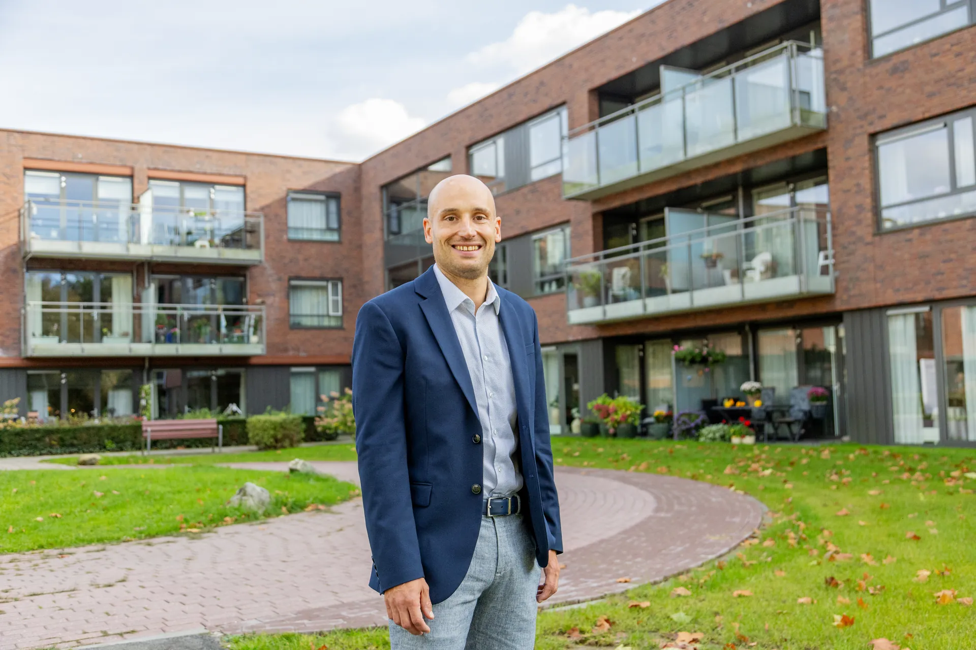 Thijs Logtenberg in colbert op het terrein van een zorglocatie.